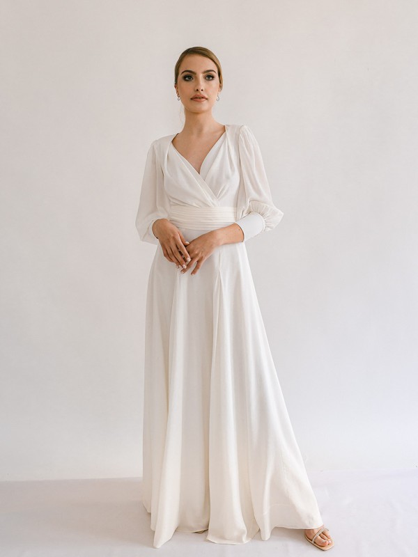 Elegantes Brautkleid mit langen Ärmeln, Wickeloberteil und weitem Rock aus fließendem Stoff.