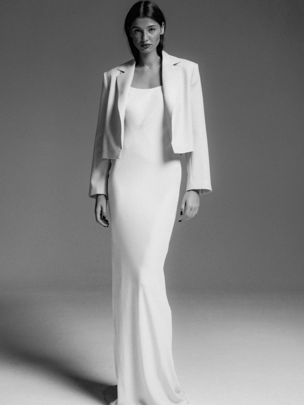 Clean-Brautkleid mit schlichtem glattem Design und passendem Blazer, minimalistische moderne Silhouette für eine elegante Braut, Schwarzweiß-Aufnahme vor neutralem Hintergrund